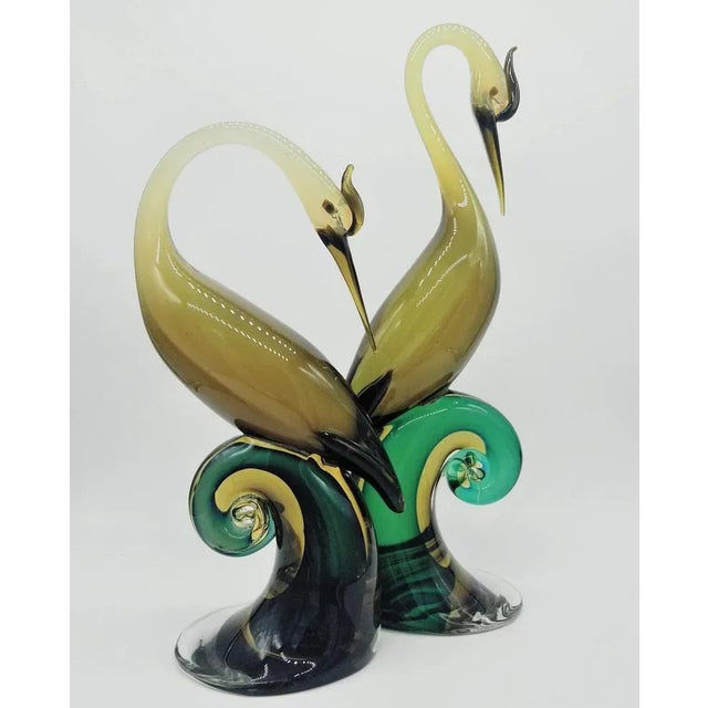 Pair of birds in sommerso opalescent-dark-yellow into transparent light-brown, each of them standing on a curled branch in...