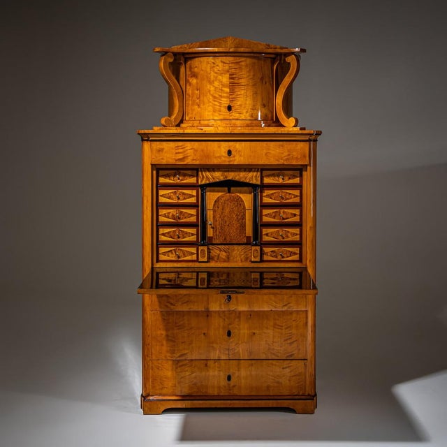 Biedermeier secretary desk in birch veneer featuring a three-drawer base, flat fall-front writing surface, and a top...