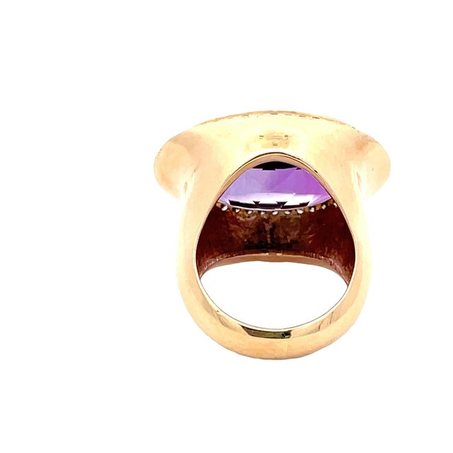 Striking 14K yellow gold ring featuring a large oval-cut amethyst center stone, framed by a delicate diamond halo. Bold...