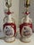 A Pair of vintage mid-century ceramic table lamps featuring ornate rococo scrollwork, iridescent red glaze, and hand-...
