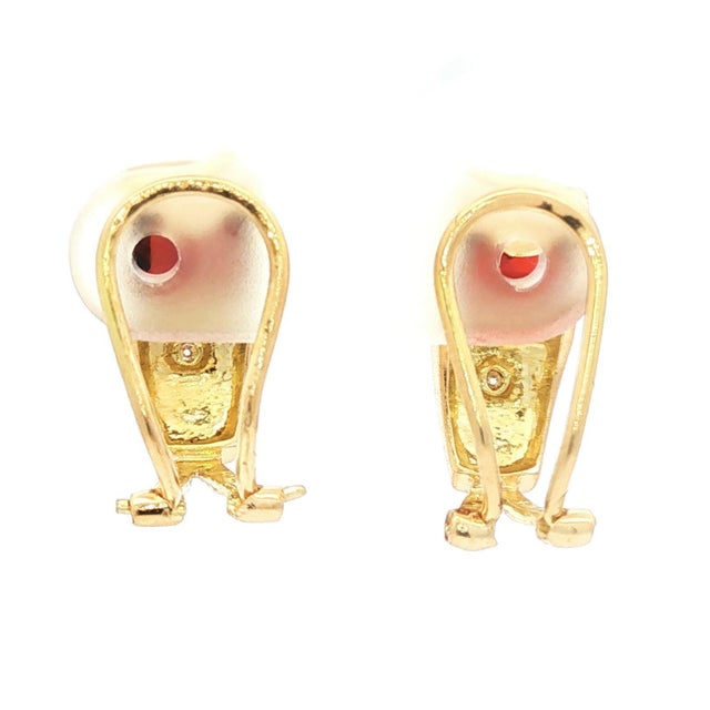 A pair of clip-on earrings crafted from 14k yellow gold. The design features a checkerboard faceted, cushion-cut garnet...
