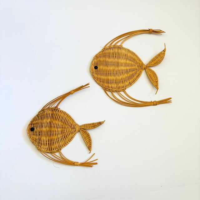 A set of 2 vintage wicker wall hangings in the shape of fish. Measurements: 9"W x 9"H x .25"D 8"W x 9"H x .25"D