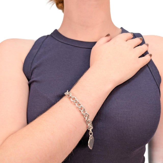 A fine signed silver chain link bracelet. By Tiffany & Co. In sterling silver. With a heart shaped tag or charm. Secured...