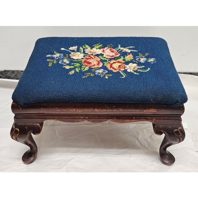 A 19th Century Mahogany and Blue Needlepoint Upholstered Footstool. Measures 19" in width, 14" in depth and 11" in height.