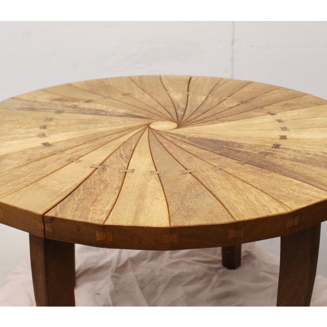 Handcrafted tabletop is a series of triangular segments that radiate from the center in a subtle pinwheell. Each segment...