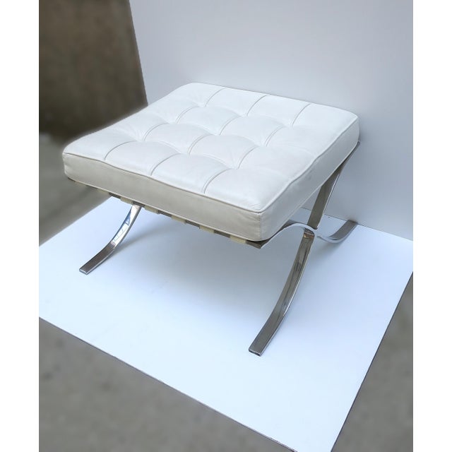 A white leather and chrome Barcelona style stool ottoman, in the Modern style, after the original iconic design by...