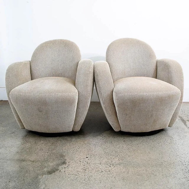 A pair of contemporary swiveling arms chairs by Larry Laslo For Directional. Composed of an overall textured tan / off...