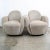 A pair of contemporary swiveling arms chairs by Larry Laslo For Directional. Composed of an overall textured tan / off...