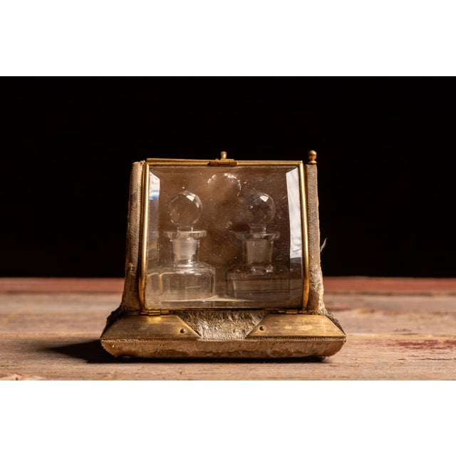 Early 20th-century vanity casket featuring a hinged beveled glass lid, gilt metal framework, and a textured fabric-covered...