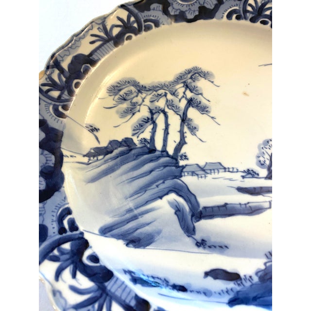 This exquisite Japanese Arita porcelain plate features a classic blue-and-white design, showcasing a serene landscape with...
