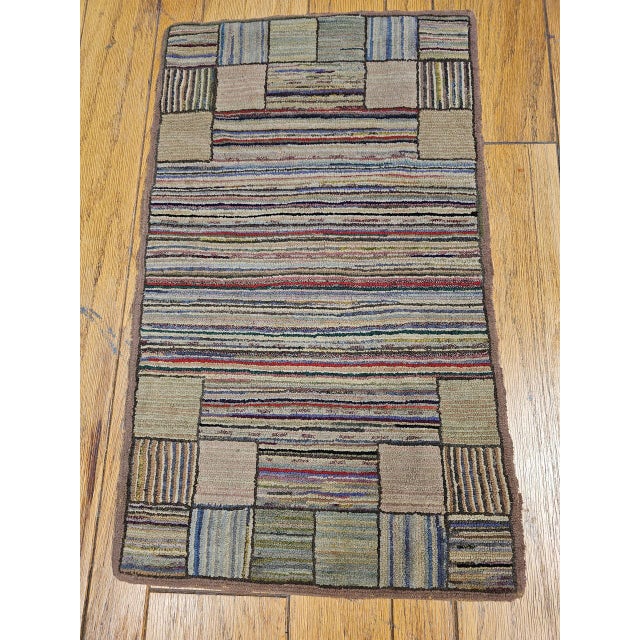A beautiful vintage American hand-hooked rug from the early 20th century, meticulously handcrafted in a classic stripe...