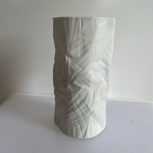 The vase features a paper relief or crumpled textile pattern with a matte bisque finish on the exterior and a glazed...
