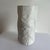 The vase features a paper relief or crumpled textile pattern with a matte bisque finish on the exterior and a glazed...