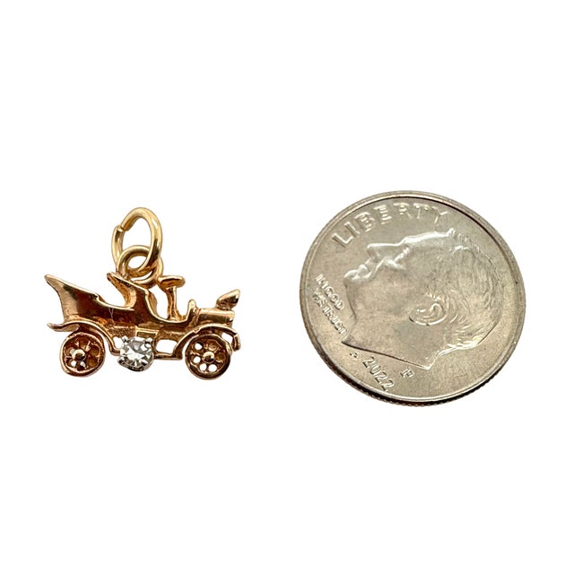 A miniature vintage 14K gold charm shaped like an antique automobile, finished with a tiny prong-set diamond accent. A...