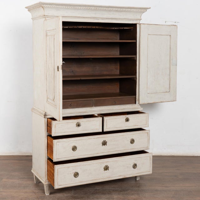 Early 19th-century Swedish Gustavian cabinet crafted in pine, featuring a newer antique white layered paint finish with...