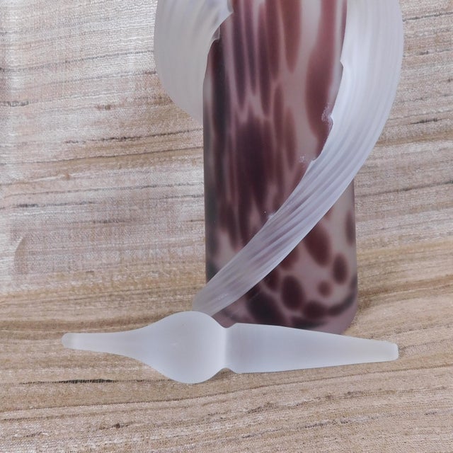 This is a tall perfume bottle done in clear glass withdark purple spots. It has two frosted glass pieces that wind around...