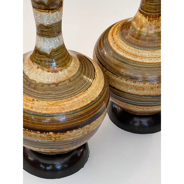 each handcrafted stoneware studio pottery piece of distinct bottle-form shape featuring a long, slender neck that tapers...