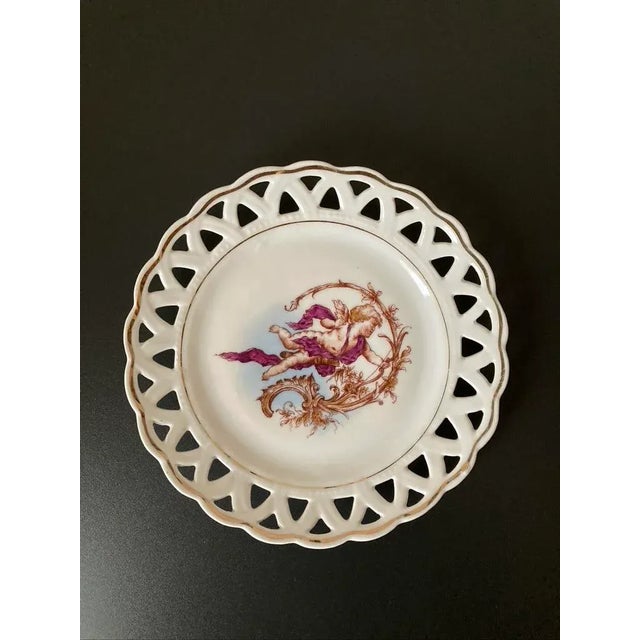 A beautiful and romantic cherub plate with lattice margin design from England, circa early 20th century. Plate has gold...