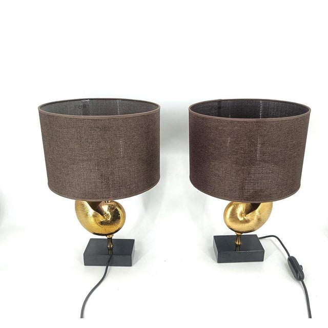 Beautiful brass nautilus shell table lamps in the style of Maison Charles. These luxurious lamps have a golden nautilus...