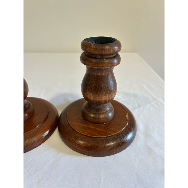 This pair of turned wood candlestick holders features a classic urn-shaped stem on a wide, round base, finished in a warm...