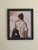 The painting depicts a young woman lost in contemplation, her profile framed against a soft, pastel background adorned...