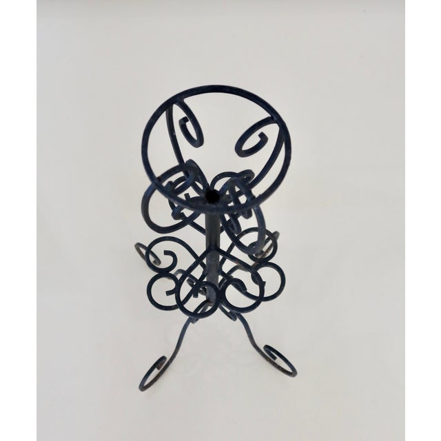 Antique black metal pedestal stand, adorned with intricate scrollwork, in a style that is both romantic and classic. It...