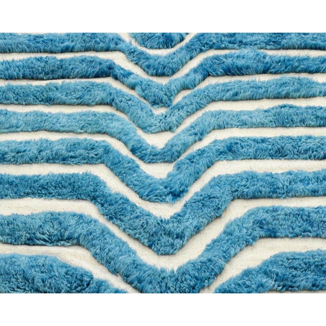 Delicate Hand-knotted wool rug, captivating with its unique design of Aegean Blue and Ivory tones alternated by flat woven...