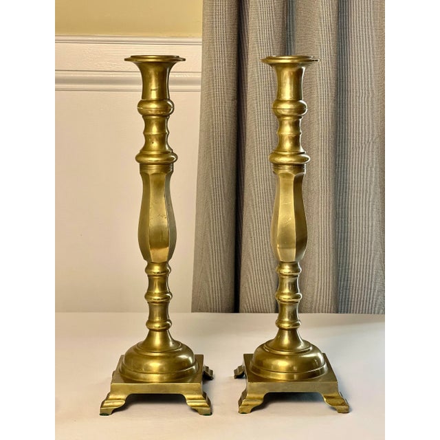 Pair of Neoclassical tall, baluster shaped brass candlesticks with a square footed base, mid to late 19th century. They...