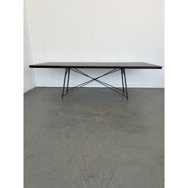 X marks the spot. A bronzed iron base strikes a spare, geo-inspired shape to support a expansive solid acacia wood top,...