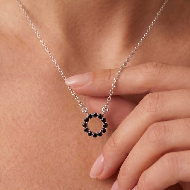 Delicately crafted in 925 Sterling Silver, this striking pendant necklace features a graceful open circle design adorned...