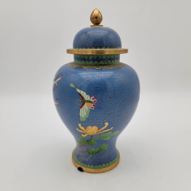 This vintage cloisonné urn features intricate floral designs on a vibrant blue backdrop, accentuated with elegant gold...