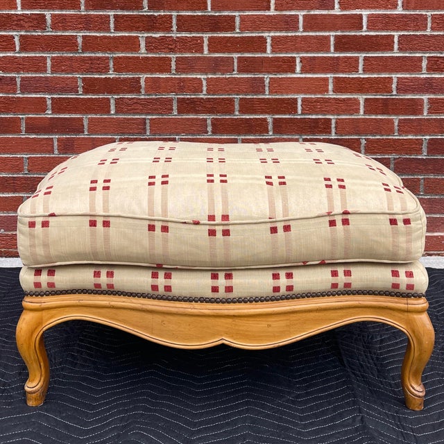 A vintage Baker Furniture French Country ottoman that goes with a bergere chair in tan & red fabric, burnished tacks, and...