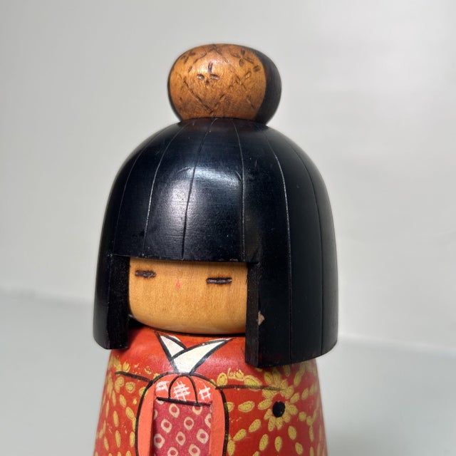 This creative-style (sōsaku) kokeshi doll, crafted by master artist Kazuo Takamizawa, depicts a young girl with a...