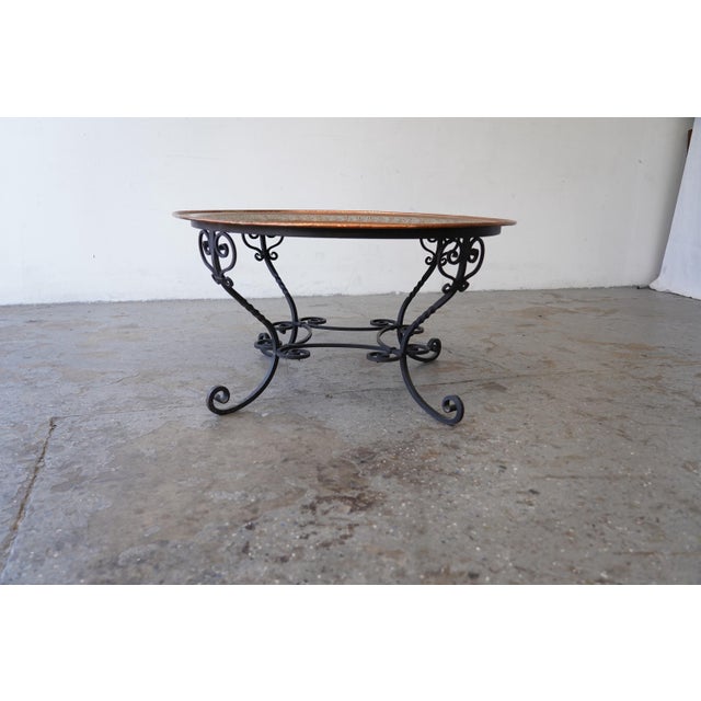 Beautiful 1950s Moroccan coffee table featuring a large hand-worked copper tray top set on an elegant wrought iron base....