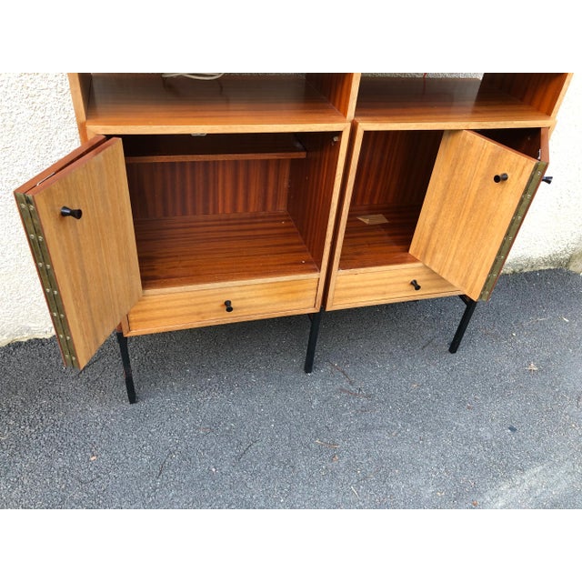 This teak bookcase features two glass sliding doors, two cabinets with double folding doors and three drawers.
