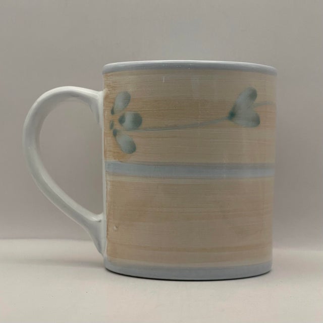An Italian ceramic coffee mug made by Caleca Ceramics decorated with a hand-painted vine pattern on a peach background.