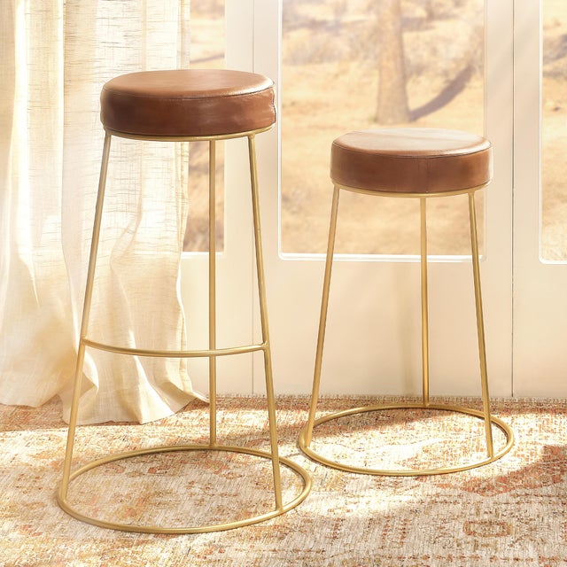 These unique stools feature a comfortably padded round seat in top-quality leather that tops an asymmetrical tri-legged...