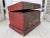 An Asian chest or box with a red painted ground and decorated with a fierce foo dog set within a geometric border...