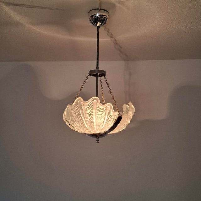Elegant pendant lamp with a decoratively curved, shell-shaped glass shade made of frosted, milky glass. The finely ribbed...