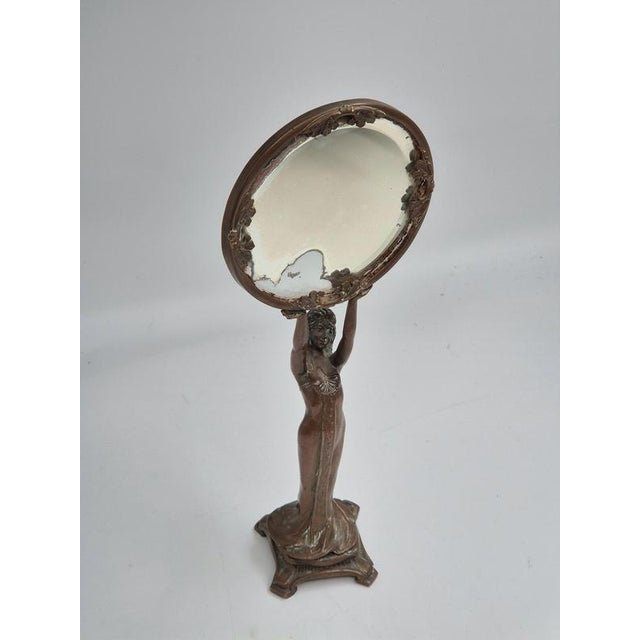 A figural vanity mirror in bronze, Art Nouveau early 1900s. Woman holding mirror with beautiful details. The glass is...