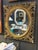 Vintage oval mirror with an ornate carved wood frame finished in gold leaf. Features intricate scrollwork and layered...