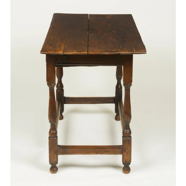 The rectangular overhanging top over a frieze drawer; raised on ring-turned legs joined by stretchers. Replaced hardware.