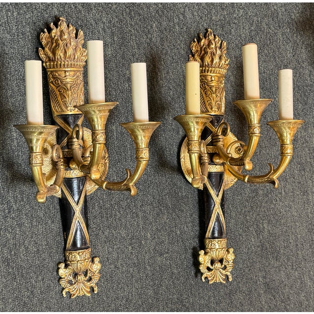 Design Plus Gallery presents a Pair of Brass Torch Wall Sconces in the French Neoclassical Style. French Neoclassical...