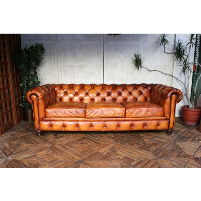 A stunning vintage Chesterfield-style sofa, upholstered in beautifully aged distressed brown leather. This classic piece...