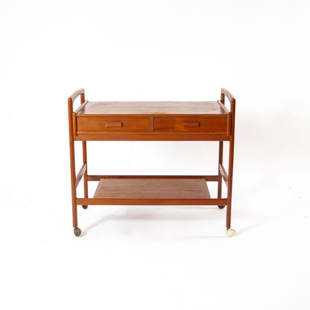 This authentic 1960s serving trolley embodies the refinement of classic Danish design. Crafted from exquisite teak wood...