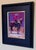 This artwork captures a moment in a vibrant rodeo scene, where a rider in a pink shirt sits atop a horse, exuding a sense...