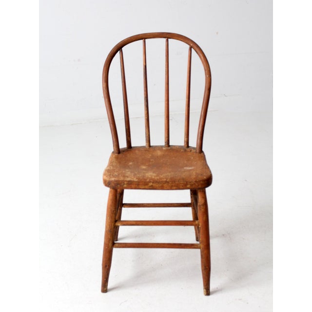 This antique bow back Windsor chair, a classic farmhouse piece, charms with its round spindle back and time-worn painted...