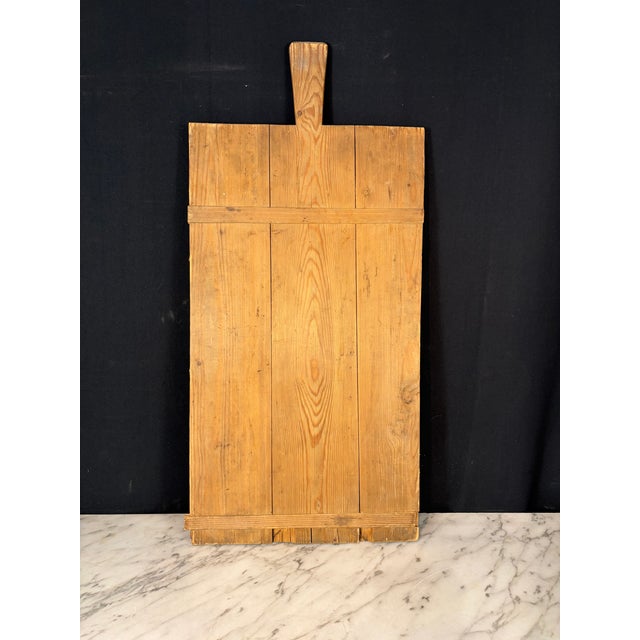 French rectangular bread board or charcuterie board, handcrafted from solid hardwood pine with a shaped handle and a warm,...