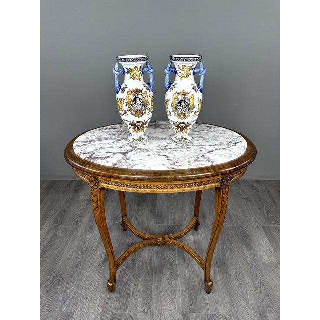 An elegant pair of polychrome earthenware vases, baluster-shaped, adorned with a rich Renaissance-inspired design. The...