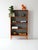 Vintage 1950s Scandinavian teak bookcase. The linear structure features a gray background that contrasts with the warm...